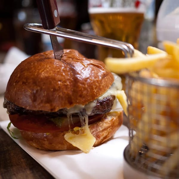 A Burger Palace cheeseburger with melted cheese, a knife, and a side of fries.
