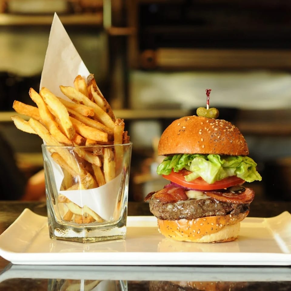 A Burger Palace bacon cheeseburger with lettuce, tomato, and onion, served with a side of fries.